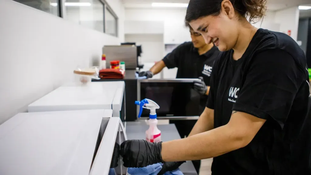 Professional cleaners in Walker's Cleaning uniforms wiping down commercial kitchen surfaces in Sydney